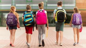 image of children wearing backpacks walking up to school