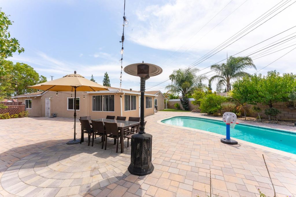 view of backyard with dining table, heater and pool