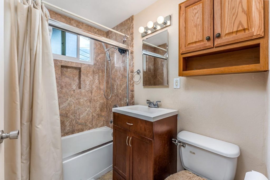 bathroom with single vanity, tub and shower combo, and toilet