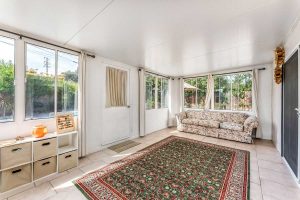 sun room with rug, couch and lots of windows looking out