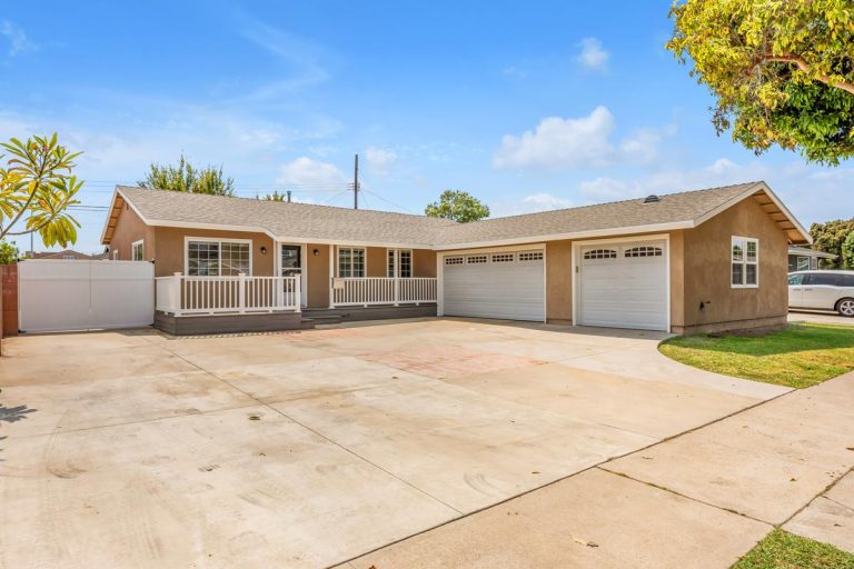 front of house showing garage doors, rv gate, and large drive way