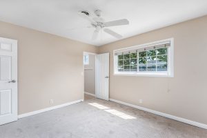 empty room with window, doors, and ceiling fan
