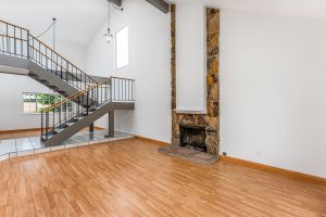 empty living room with fireplace and open staircase and dining room in the background