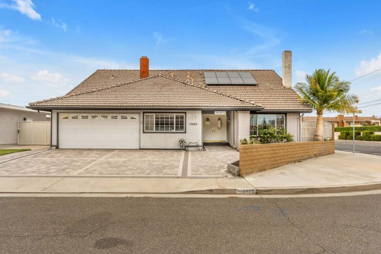 front of house showing large driveway and solar panels