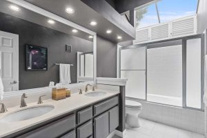 bathroom with double sinks, shower/tub combo and toilet