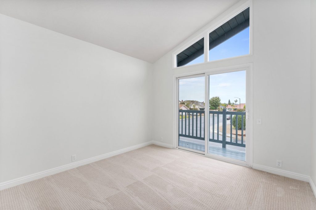 empty bedroom in room with slider to balcony and vaulted ceilings