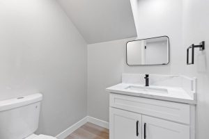 updated bathroom with sink, square mirror and toilet
