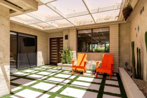 entryway with pavers and grass, two orange chairs and covered patio