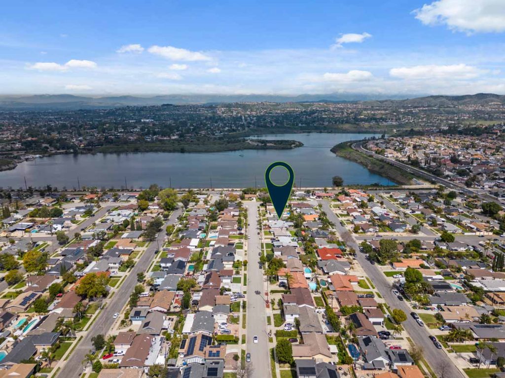 aerial view of neighborhood with lake in the background and arrow pointing to house for sale