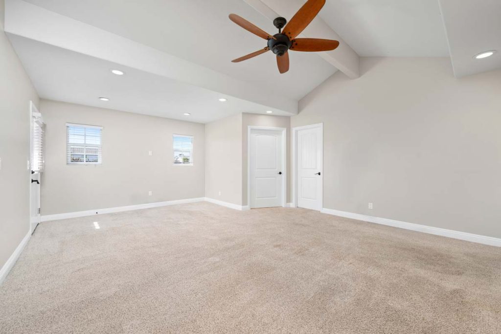 carpeted room with ceiling fan and white walls