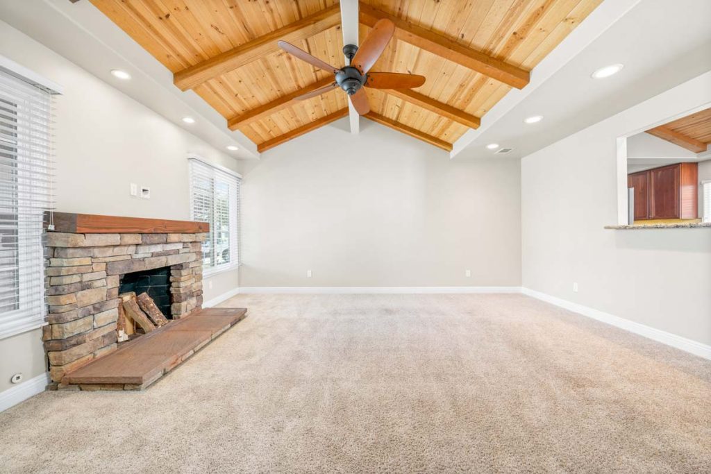 carpeted room with fireplace and vaulted, wood planked ceiling