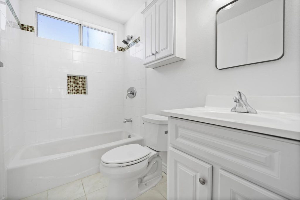 full bathroom with white walls, cabinets, tub shower combo and toilet
