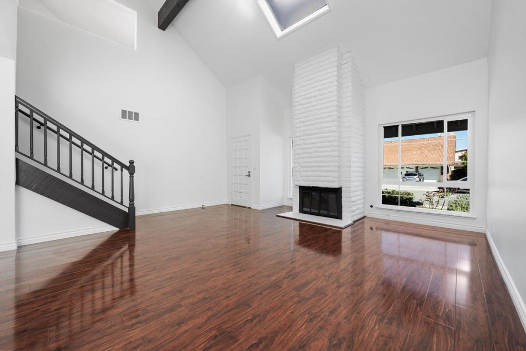 vaulted ceiling in large room with fireplace and stairs leading to second level