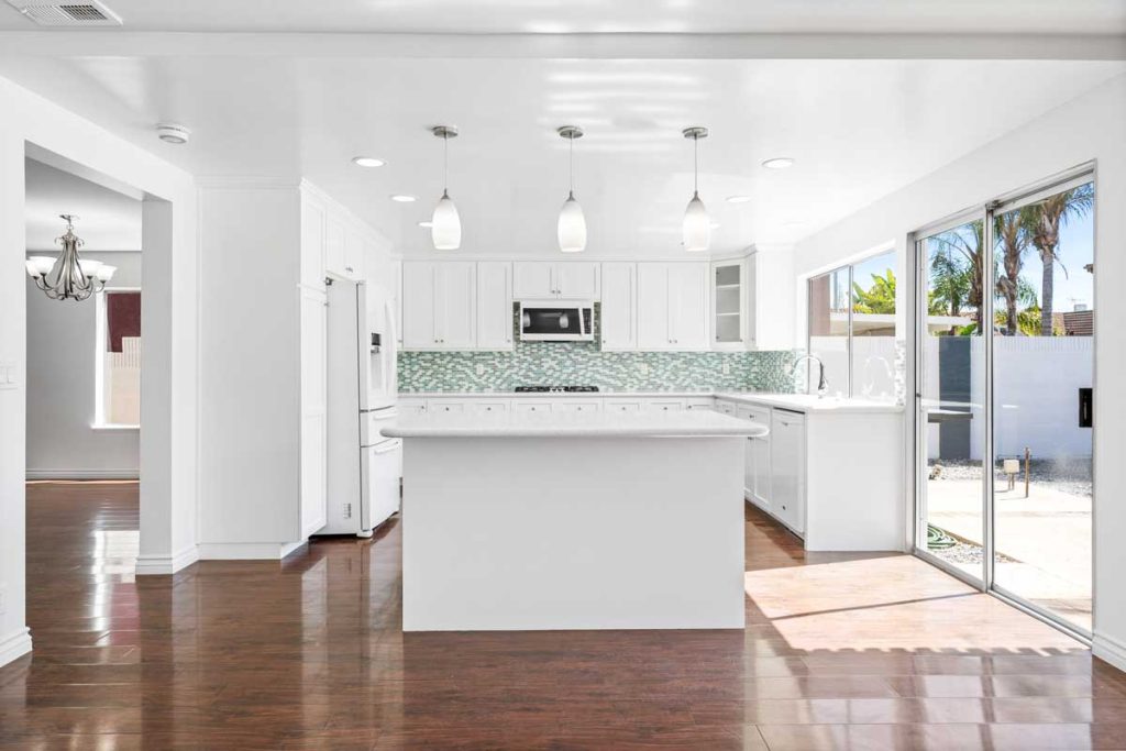 white kitchen with island and overhead lighting