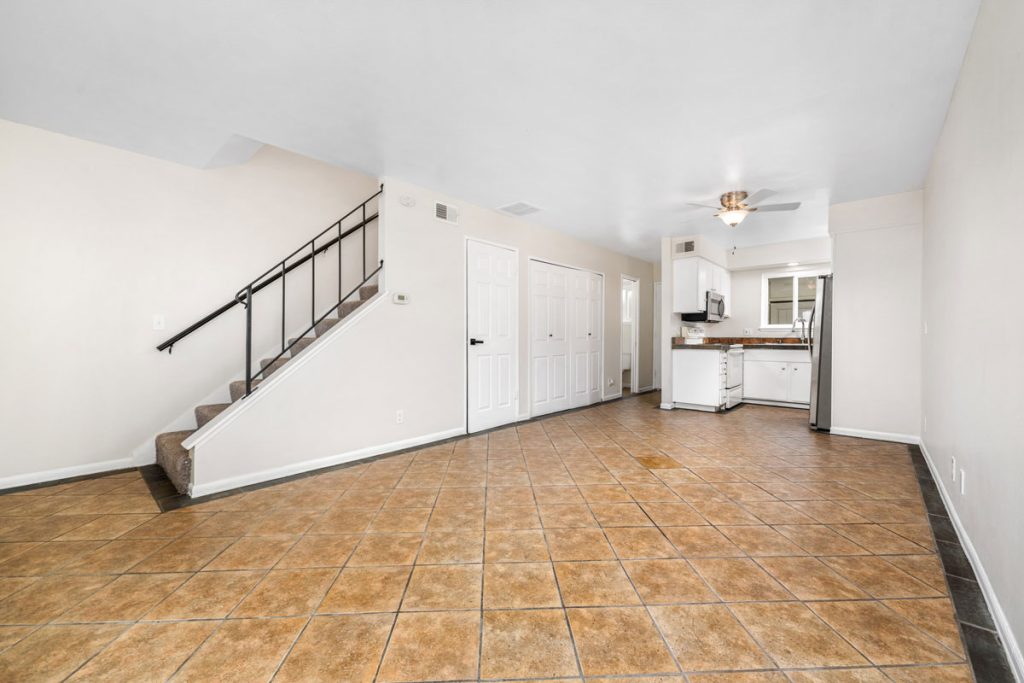 brown tile flooring with kitchen, doors to closet and laundry and stairs leading to a second level