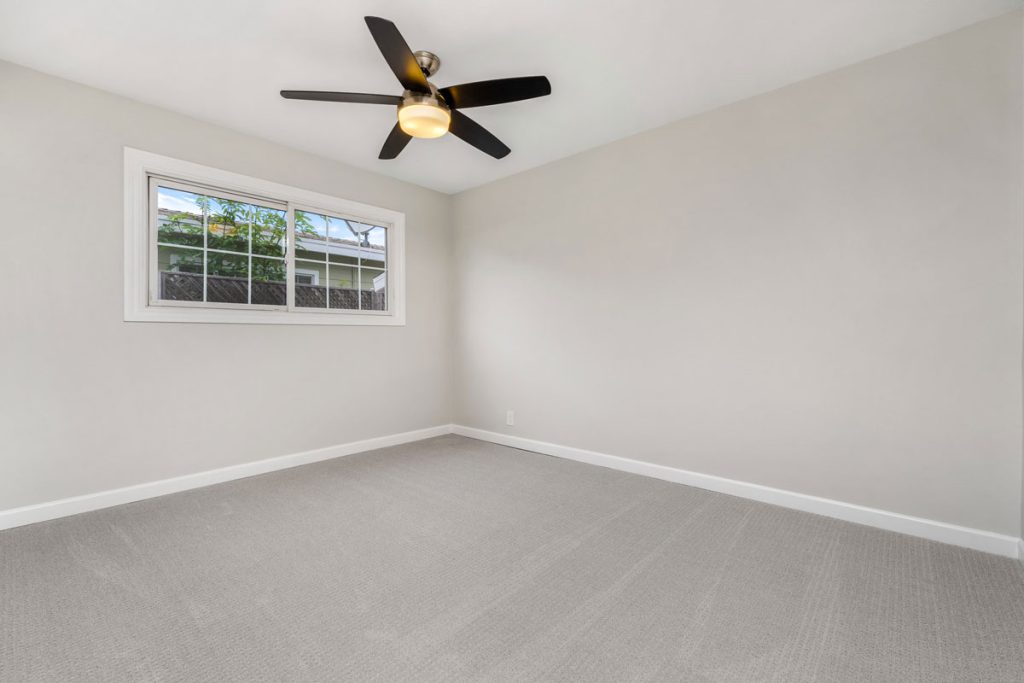 empty bedroom with carpet, window, and ceiling fan