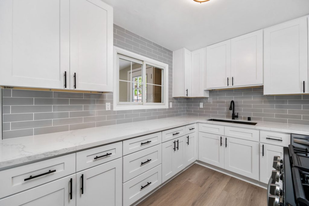 white kitchen with gray subway tiles and black hardware