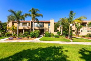 front exterior of 16883 Bluewater Lane #27, Huntington Beach with grassy area and palm trees