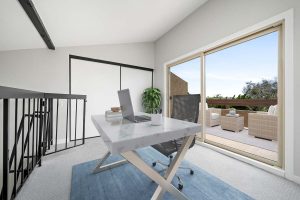 staged loft area with sliding glass door to balcony and desk