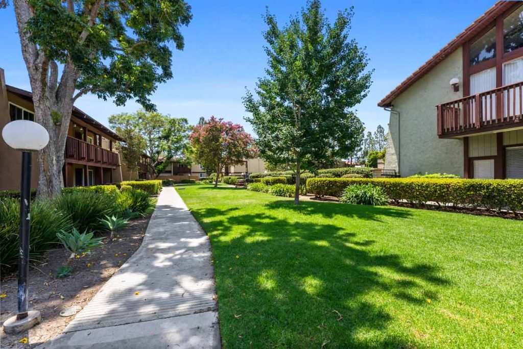 condo community with trees, green grass and walking path through neighborhood