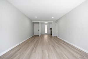 entry to condo showing hard flooring, bare walls, and entry to kitchen