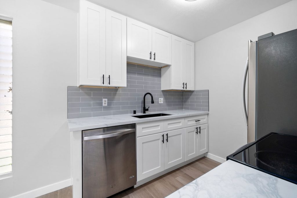 updated kitchen with stainless steel appliances and white cabinets and grey tile backsplash