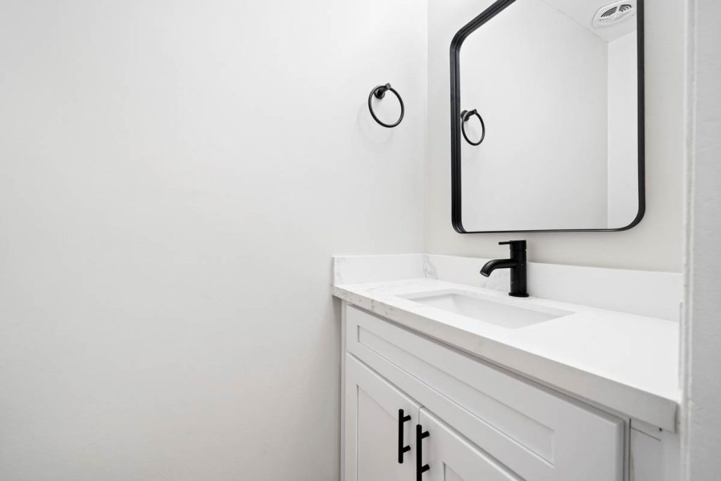 updated bathroom showing single vanity and matte black rimmed mirror