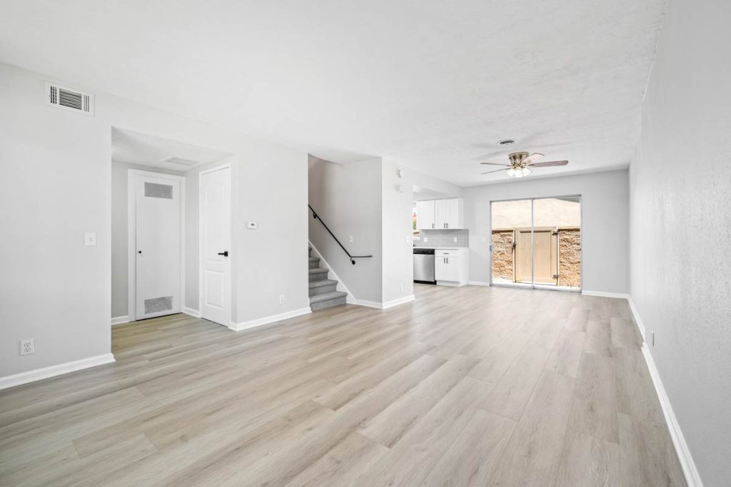 empty living space with laminate flooring, entrance to stairs going up, and a sliding glass door to patio