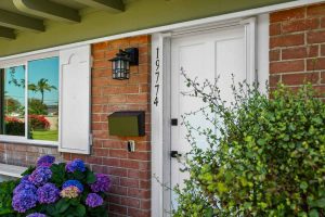 view of white front door with red bricks surrounding and olive green trim