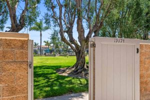 view of community pool and large grassy area from gate of patio