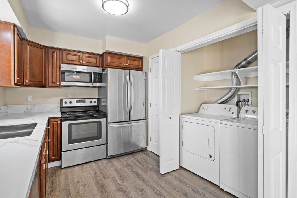 kitchen with stainless appliances, stone countertops and laundry closet with washer and dryer