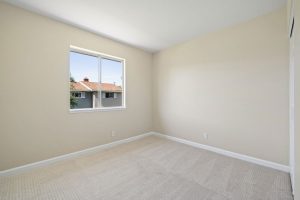 empty bedroom with window, cream colored walls and carpet