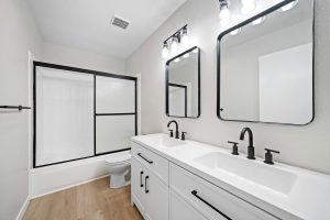 updated white with black trim bathroom showing double vanities and mirrors