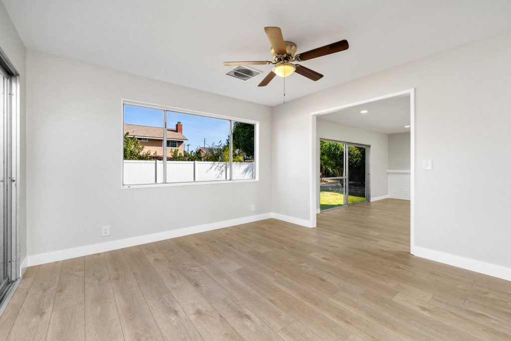 empty room with ceiling fan, neutral colored walls and hardwood floors. Window overlooking backyard