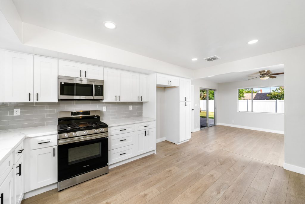 updated kitchen showing white cabinets, stainless steel appliances and hardwood flooring