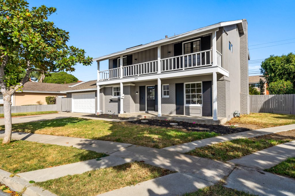 front of colonial style home for sale showing grey exterior with white trimmed second level balcony