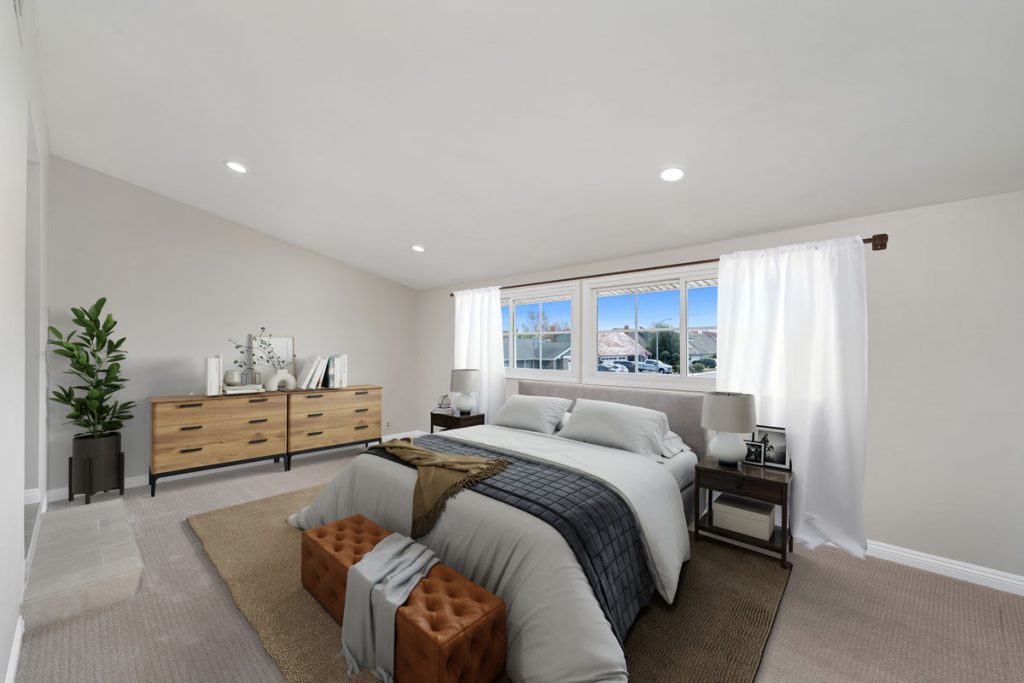 staged master bedroom with bed on top of a rug with a window behind