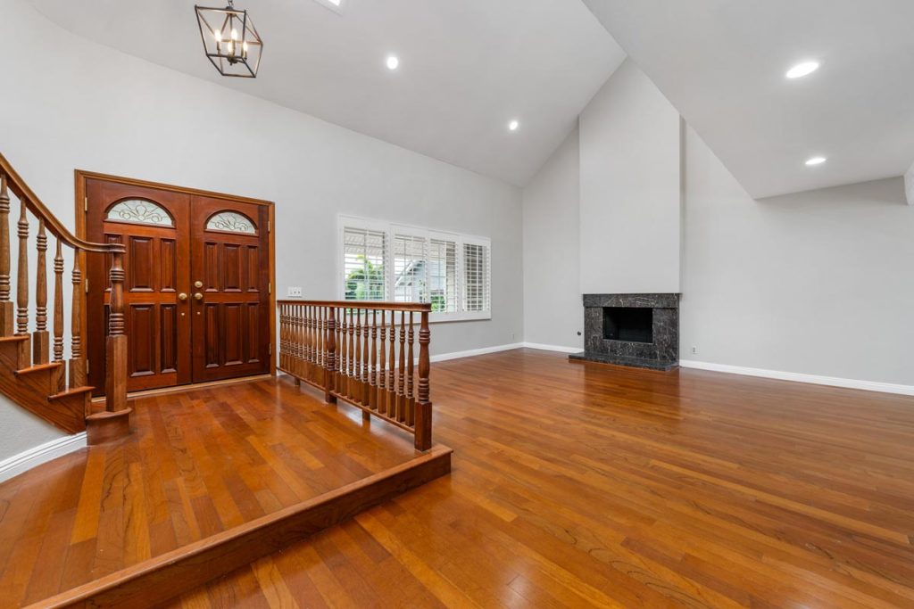 interior entry of home showing double wood front doors, wood floors, staircase and fireplace