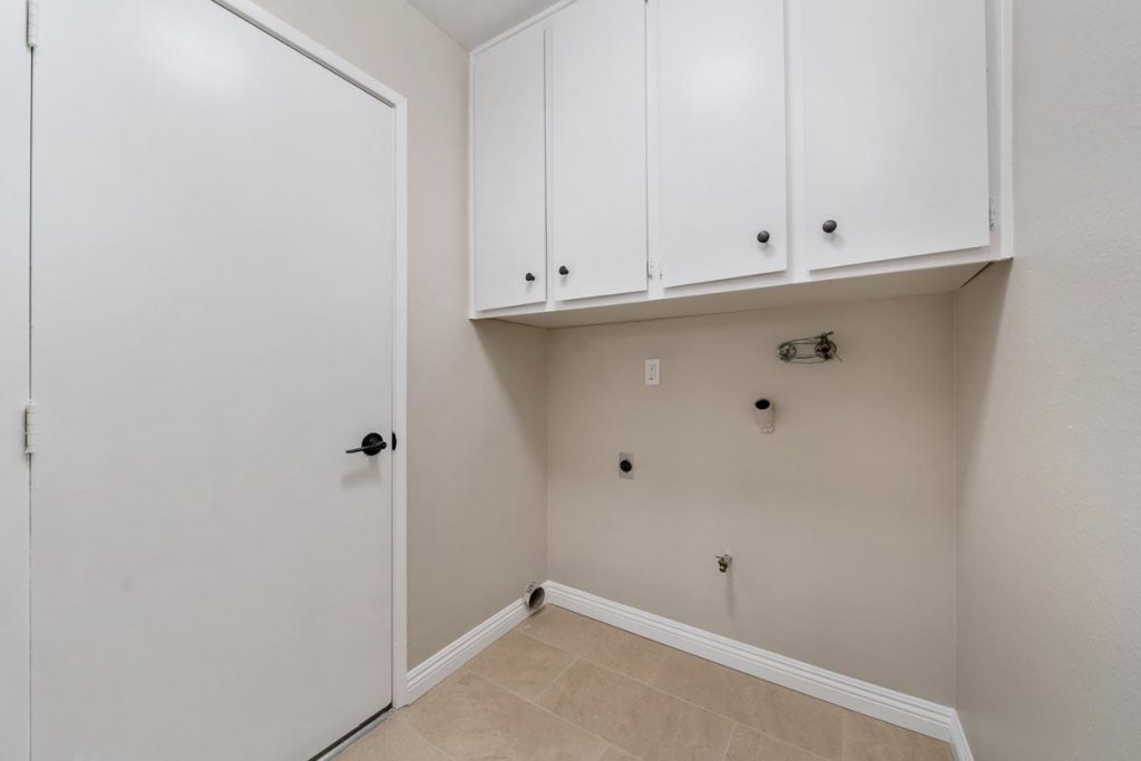 laundry room showing hook-ups and white cabinets