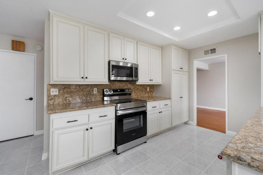 kitchen with white cabinets and tan counters and backsplash