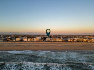 drone view of home from over the ocean with an arrow pointing to home for sale