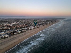 aerial view of beachfront home with ocean, sand with arrow pointing to house