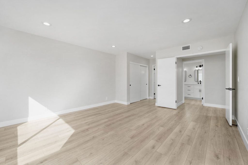 empty bedroom with light colored hard flooring and light neutral colored walls