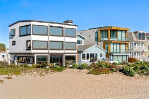 beachfront home showing three stories of window walls to view ocean