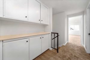 upstairs landing showing cabinetry, a carpeted hall and a door leading to a bedroom.