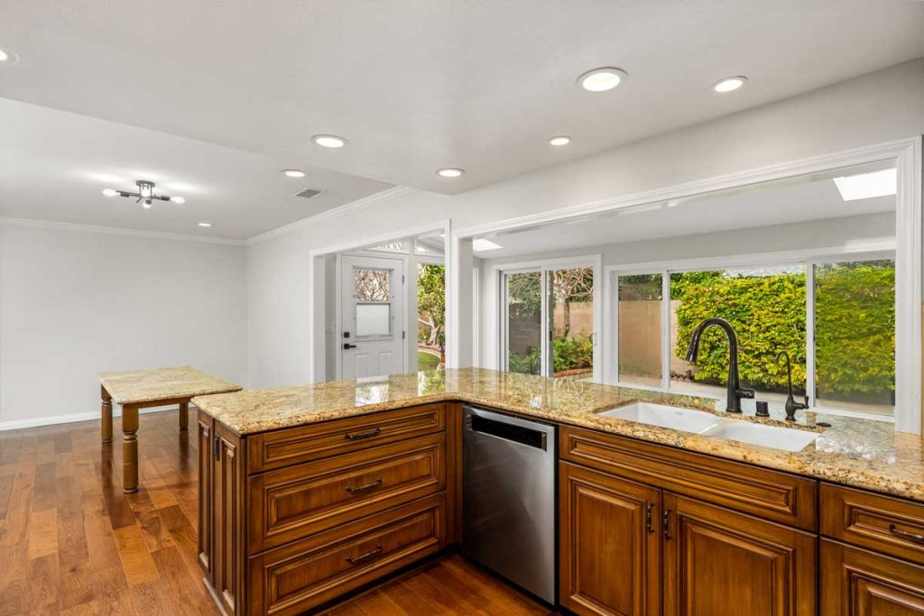 kitchen with wood cabinets, tan granite and large wall of windows overlooking the backyard