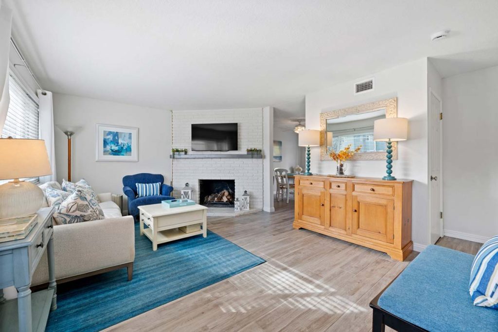 living room with neutral floors and walls, with blue accents, a fireplace and couch