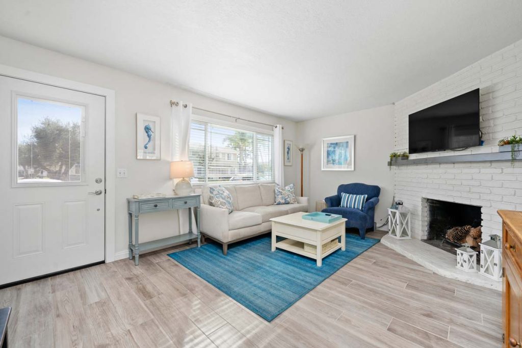 living room with neutral floors and walls, with blue accents, a fireplace and couch