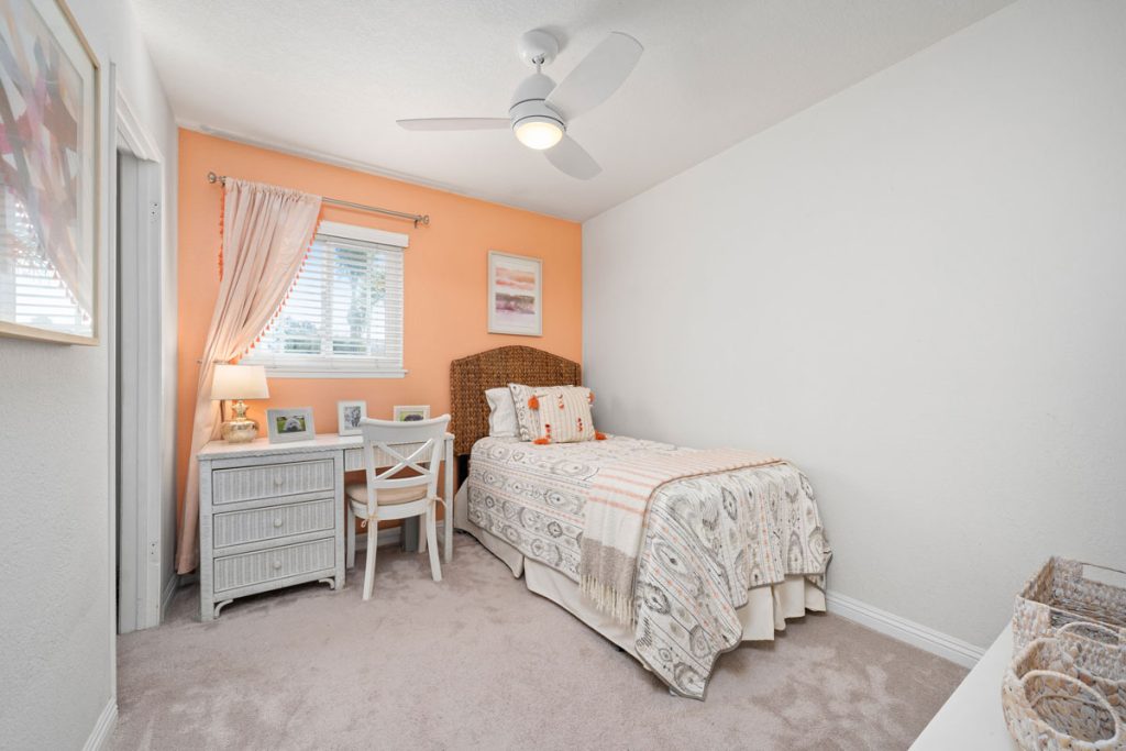 bedroom with light orange accent wall, a twin bed and small desk