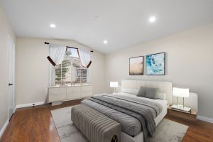 staged master bedroom with bed, night stands, dresser and window